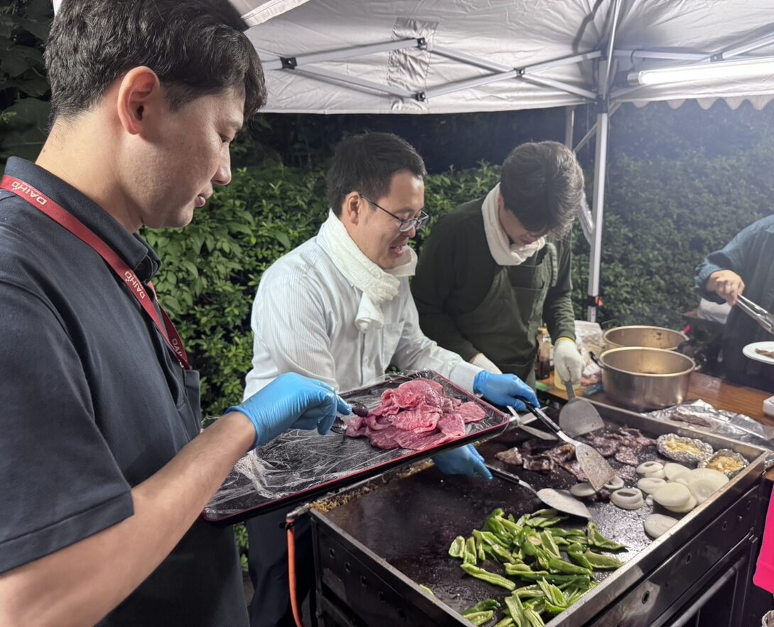 新川一丁目東町会納涼会でバーベキューの食材を焼く作業を手伝う大豊建設社員